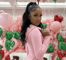 a woman in a pink outfit is standing in front of a wall of pink balloons