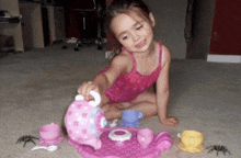 a little girl playing with a tea set on the floor