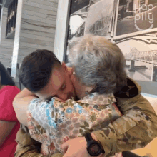 a man in a military uniform kisses a woman in front of a sign that says " hop pillu "