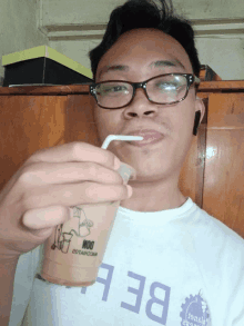 a man wearing glasses drinks from a cup that says moo