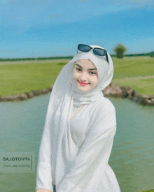 a woman wearing a white hijab and sunglasses poses for a photo