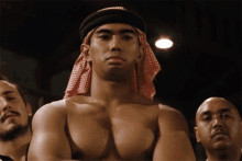 a shirtless man wearing a head scarf stands in a boxing ring