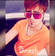 a man wearing sunglasses and an orange shirt with the name dinesh written on it