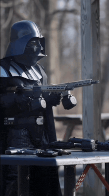 a man dressed as darth vader is holding a rifle