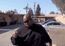 a man wearing sunglasses and a black shirt stands in front of a building