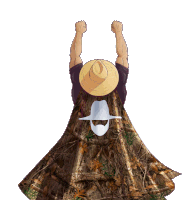 a man wearing a cowboy hat and a camouflage cape is raising his fist in the air