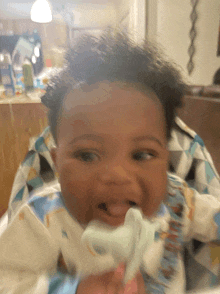 a baby in a high chair with a toothbrush in his mouth