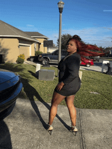 a woman in a black dress stands on a sidewalk