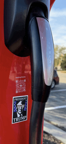 a red tesla charging station has a sticker that says president trump