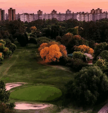 an aerial view of a golf course with buildings in the background