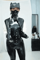 a woman in a black latex outfit is wearing a hat with ears