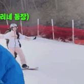 a woman is riding a snowboard on a snowy slope with a red fence in the background .