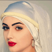 a close up of a woman wearing a white veil and red lipstick .