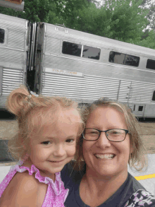 a woman holds a little girl in front of a horse trailer that says ' u.s. army ' on it