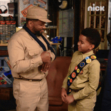 a man in a hat talks to a boy in a boy scout uniform with the nick logo in the corner