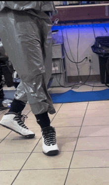 a person wearing black socks and white sneakers is walking on a tiled floor