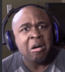 a bald man wearing headphones is making a surprised face .