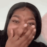 a woman is covering her mouth with her hands and laughing .