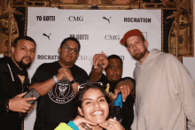 a group of people pose for a photo in front of a wall that says yo gotti cmg and rocnation