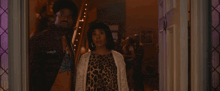 a woman in a leopard print dress stands between two men in cowboy outfits