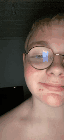 a boy wearing glasses has a reflection of a blue object in his eye