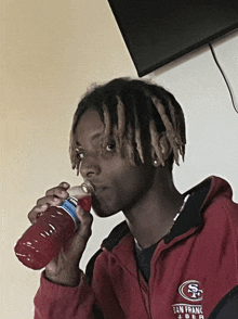 a man drinking from a gatorade bottle with the san francisco 49ers logo on his jacket