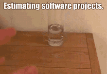 a glass of water sits on a wooden table with the words estimating software projects above it