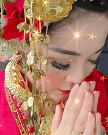 a woman in a red and gold dress is praying with her hands folded