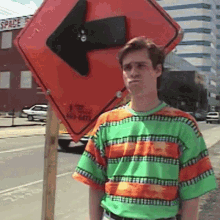 a man in a green and orange striped shirt is standing in front of an arrow sign that says space