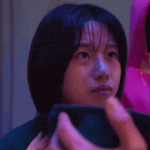 a close up of a woman 's face while holding a cell phone