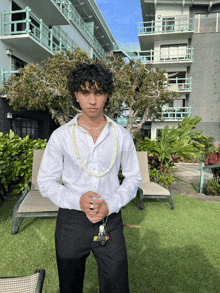 a young man wearing a white shirt and black pants is standing in front of a building