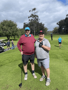 two men standing on a golf course with one wearing a hat that says ' ucsd ' on it