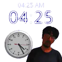 a man with glasses stands next to a clock that says 04:25 am