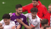 a group of soccer players are hugging each other on the field .