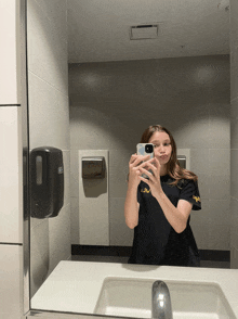 a girl taking a selfie in a bathroom with a shirt that says sw