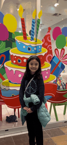 a little girl standing in front of a birthday cake