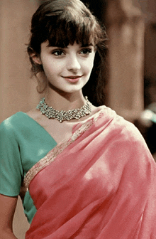 a young woman wearing a pink saree and a blue blouse