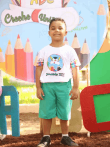 a young boy stands in front of a sign that says " creche uni "