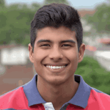 a young man wearing a red and blue polo shirt is smiling