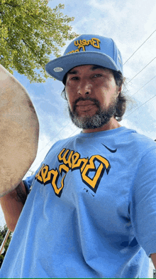 a man with a beard wearing a blue shirt that says boston