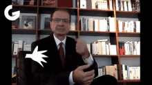 a man in a suit and tie is sitting in front of a bookshelf with a book titled encyclopedia on it