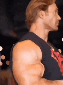 a man with a lot of muscles is wearing a black tank top and a red shirt .