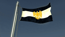 a black and white flag with a gold eagle on the top