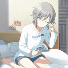 a girl is sitting on a bed looking at a cell phone