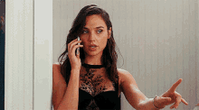 a woman in a black bra is talking on a cell phone while standing in front of a mirror .