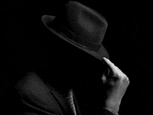 a man wearing a black hat covering his face in the dark