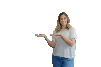 a woman in a white shirt and blue jeans is holding something in her hand