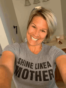 a woman wearing a grey shirt that says shine like a mother