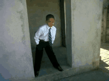 a young boy wearing a white shirt and tie is standing in a doorway