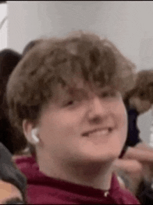 a young man wearing headphones is smiling while sitting in a crowd .